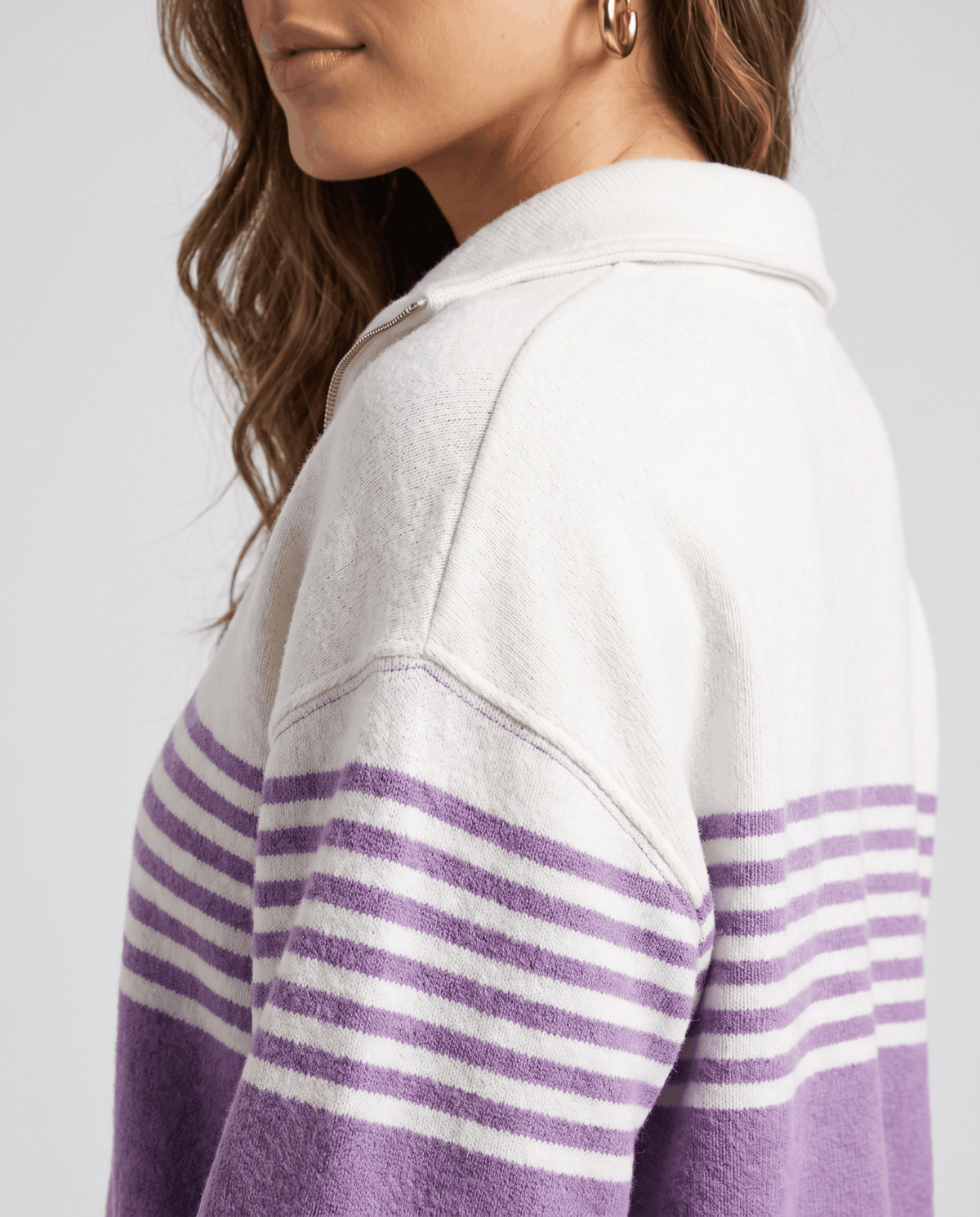 Close-up of drop shoulder and lavender horizontal stripes on an ivory knit sleeve