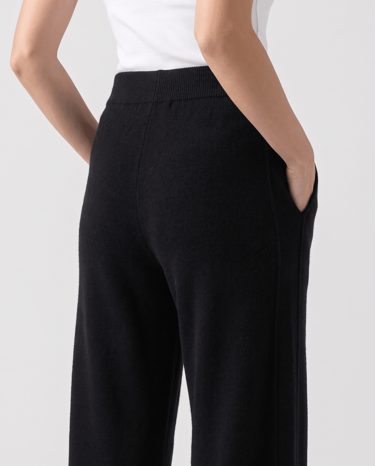 Close-up of black knit fabric at the back with hand in pocket
