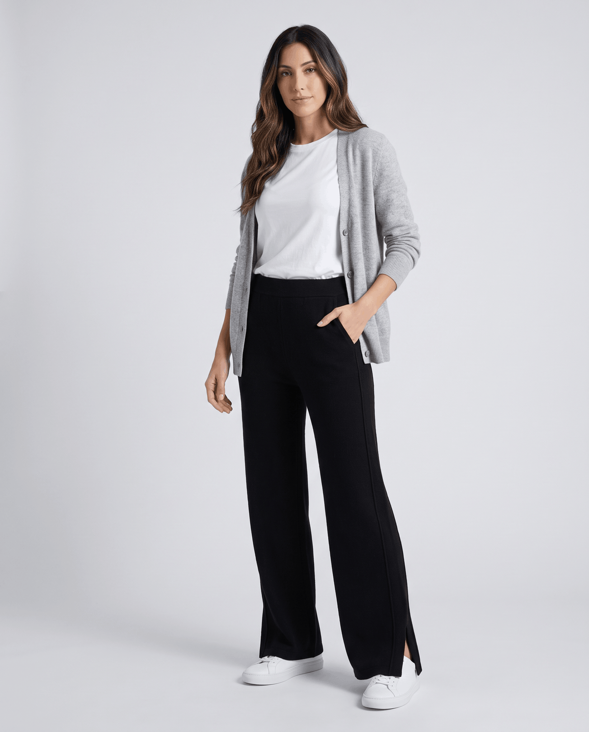 Model in gray cardigan and white tee wearing black full-length knit pants