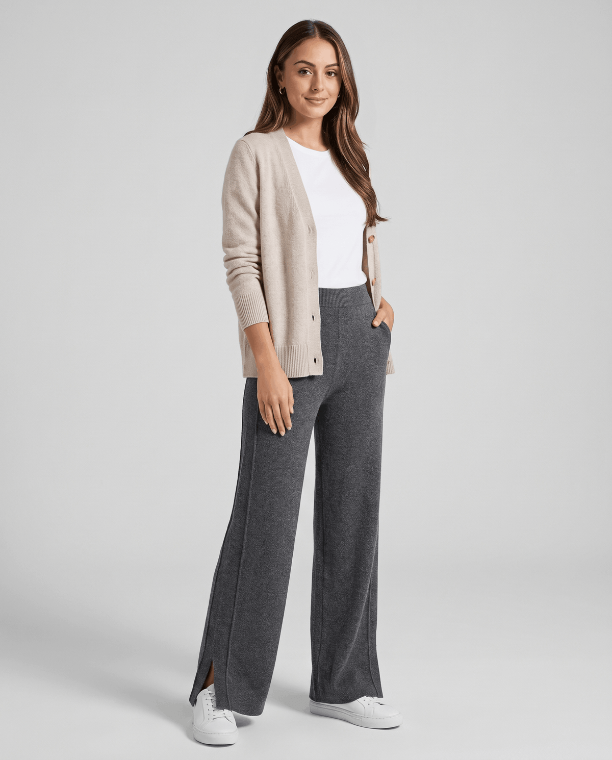 Model in beige cardigan and white tee wearing gray full-length knit pants