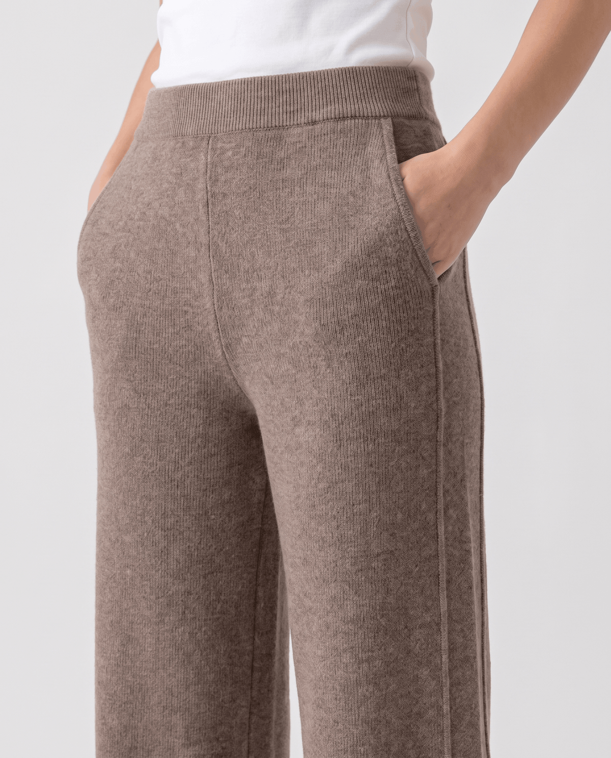 Close-up of khaki knit waistband and side pocket with model's hand tucked inside