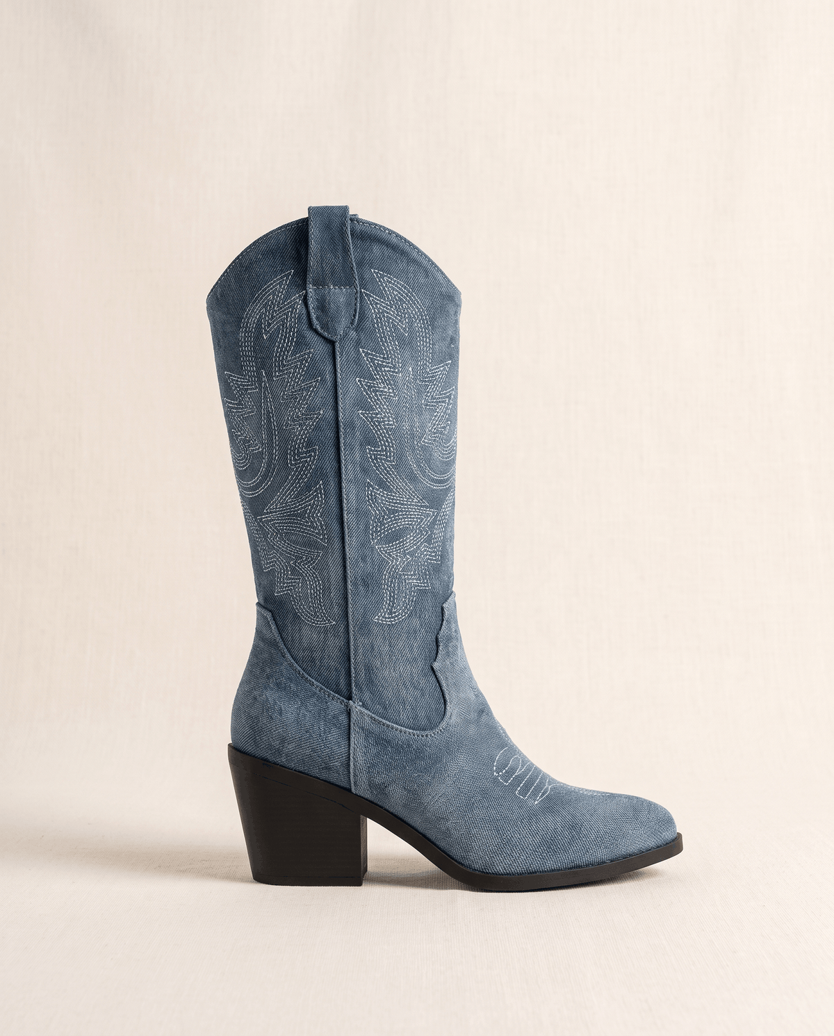 Side view of a single blue boot with stitched shaft, pointed toe and black block heel