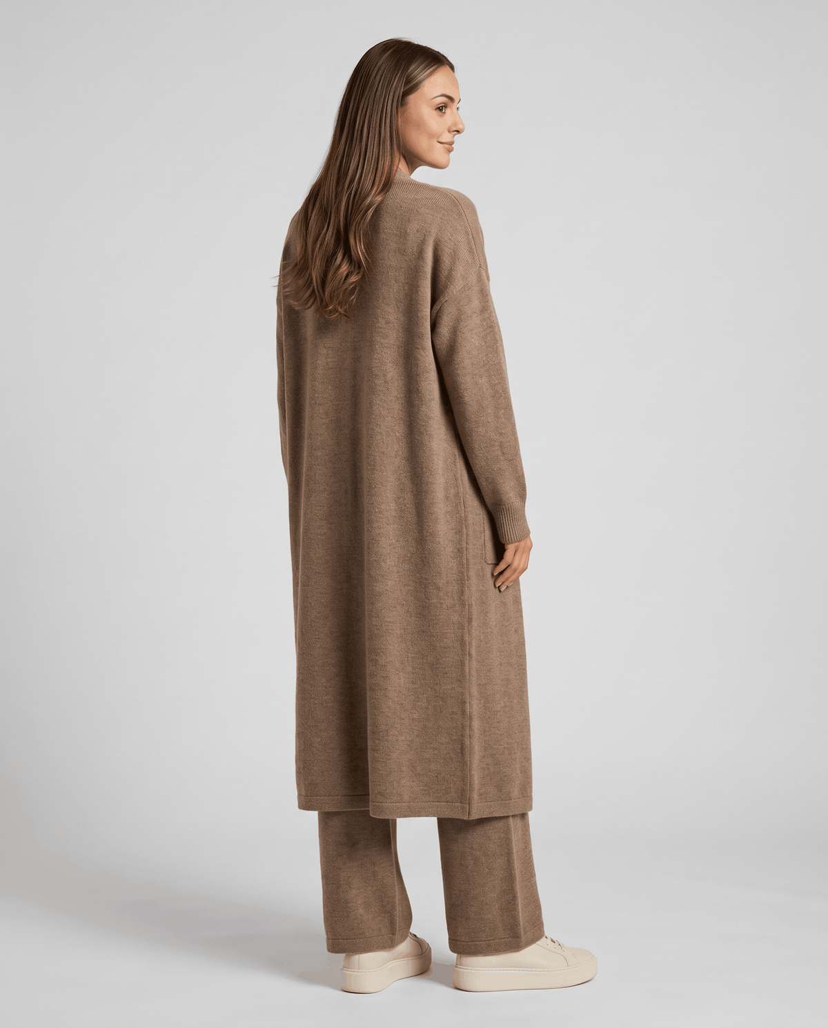 Back view of the beige long cardigan coat worn with matching wide-leg pants