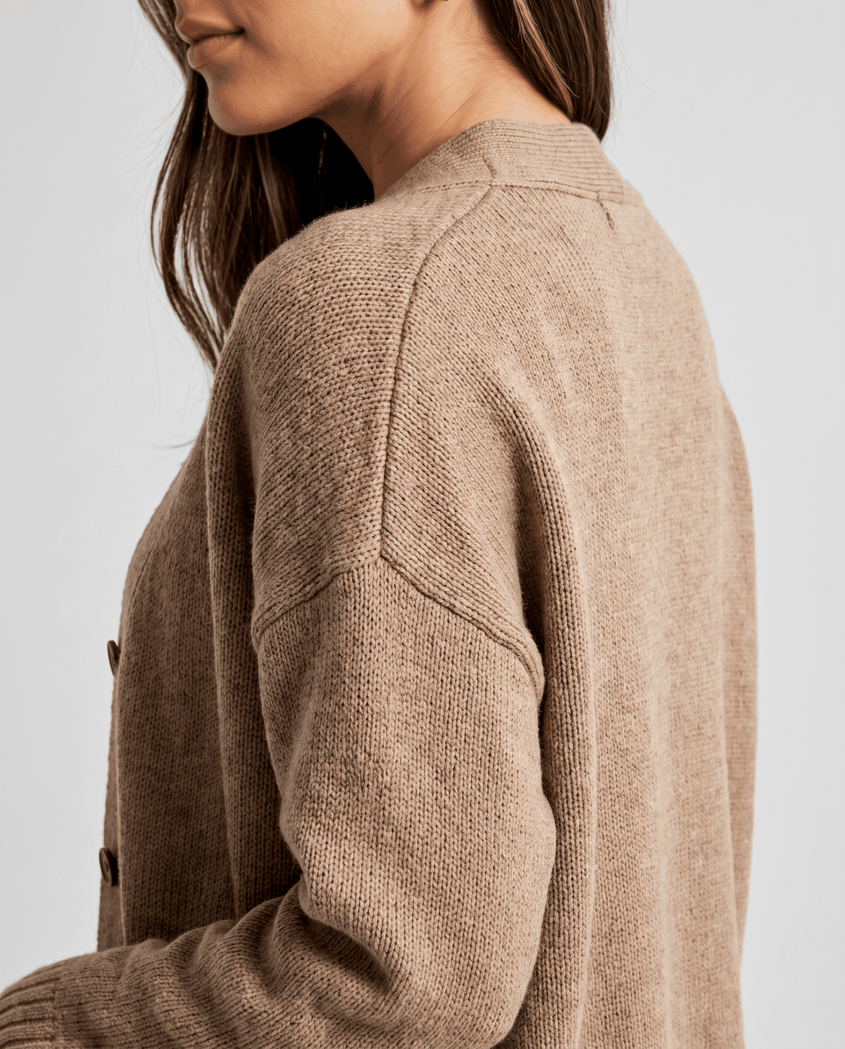 Close-up of the shoulder seam and sleeve on the beige cardigan coat