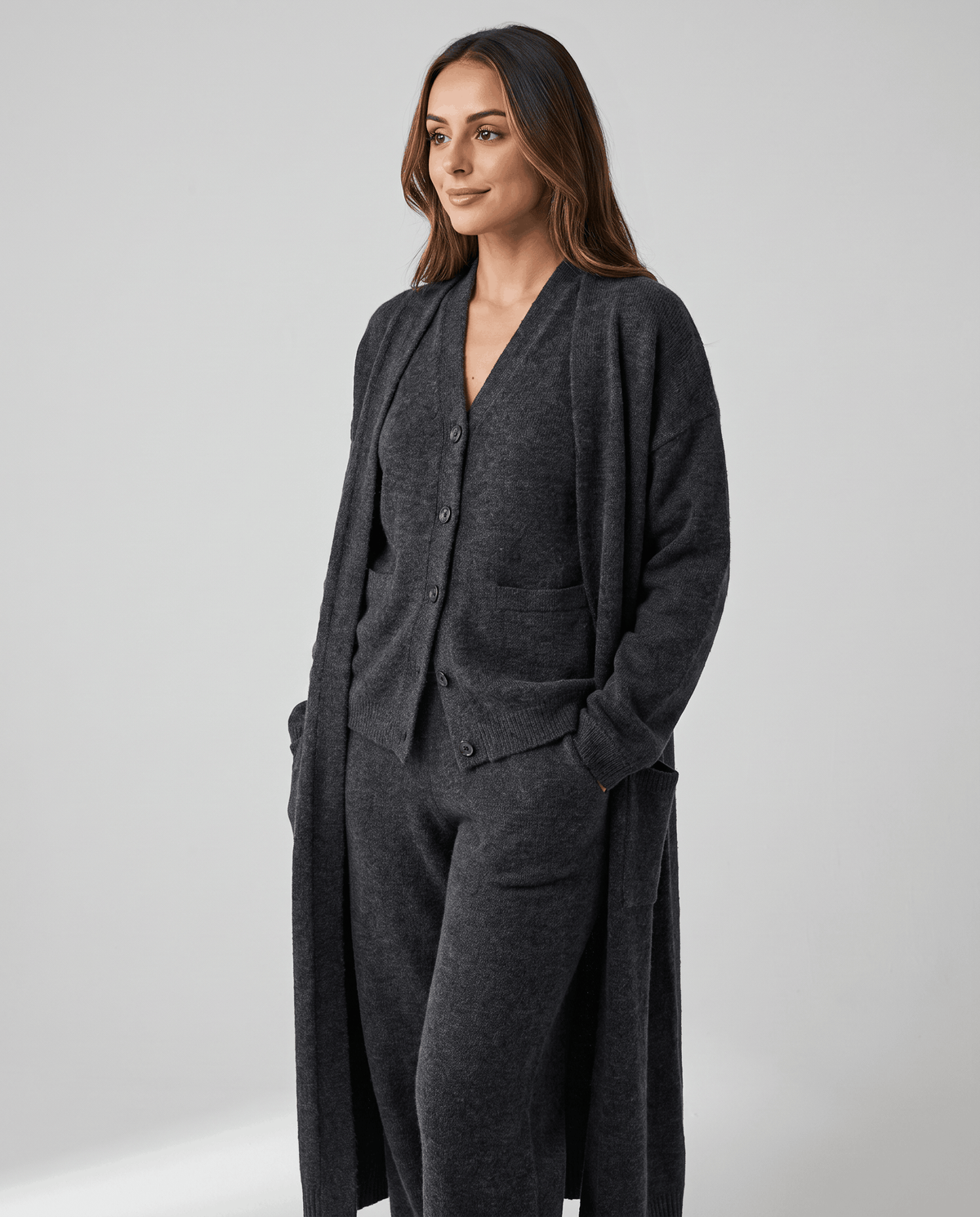 Dark gray knit vest and cardigan coat styled with hands in the pockets