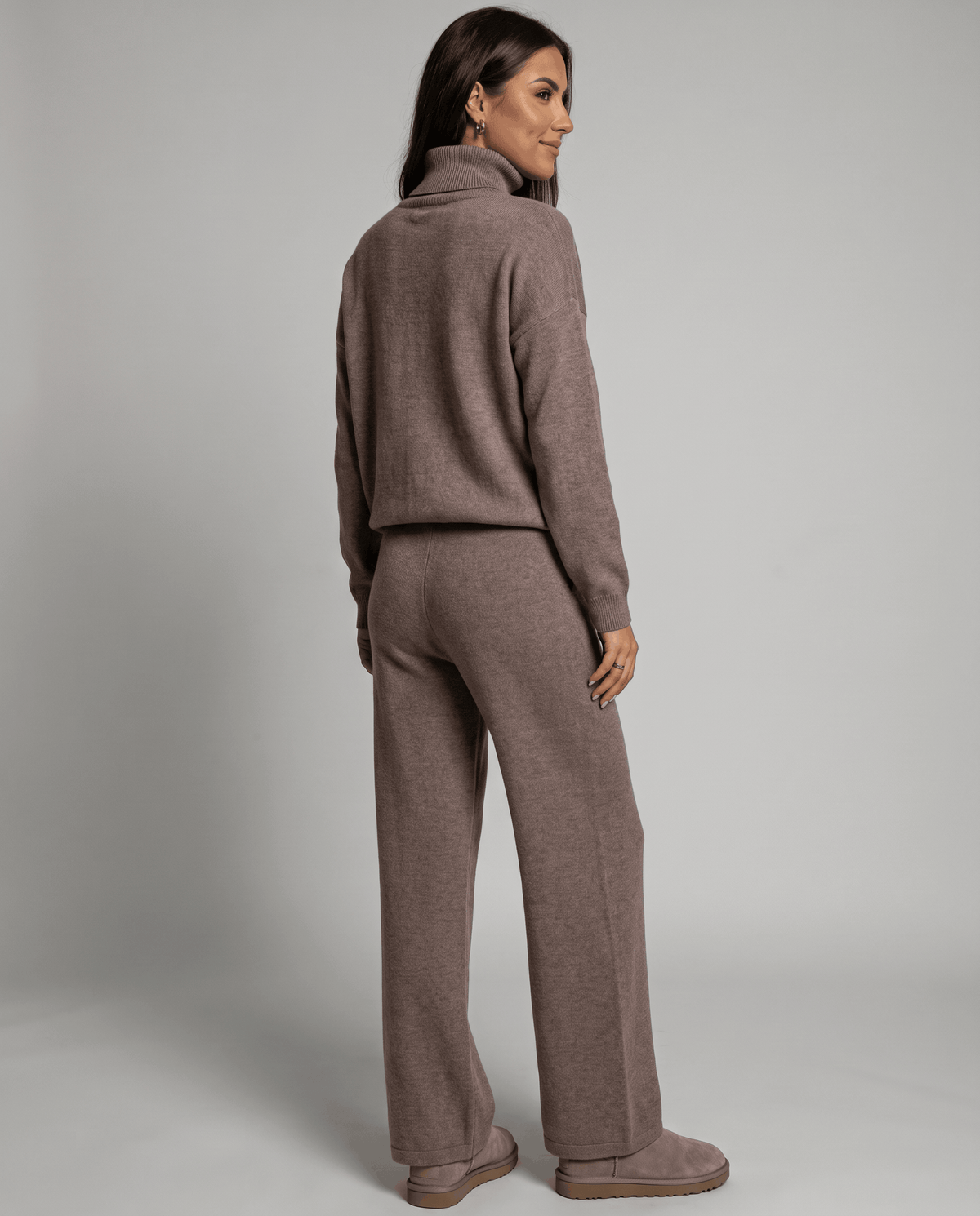 Back view of the taupe top and straight-leg pants with the model looking over her shoulder