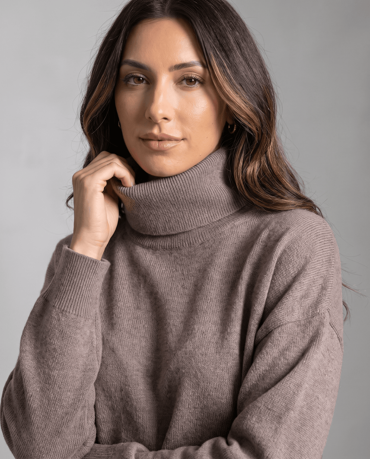 Close-up of the ribbed turtleneck collar with the model's hand at the neckline