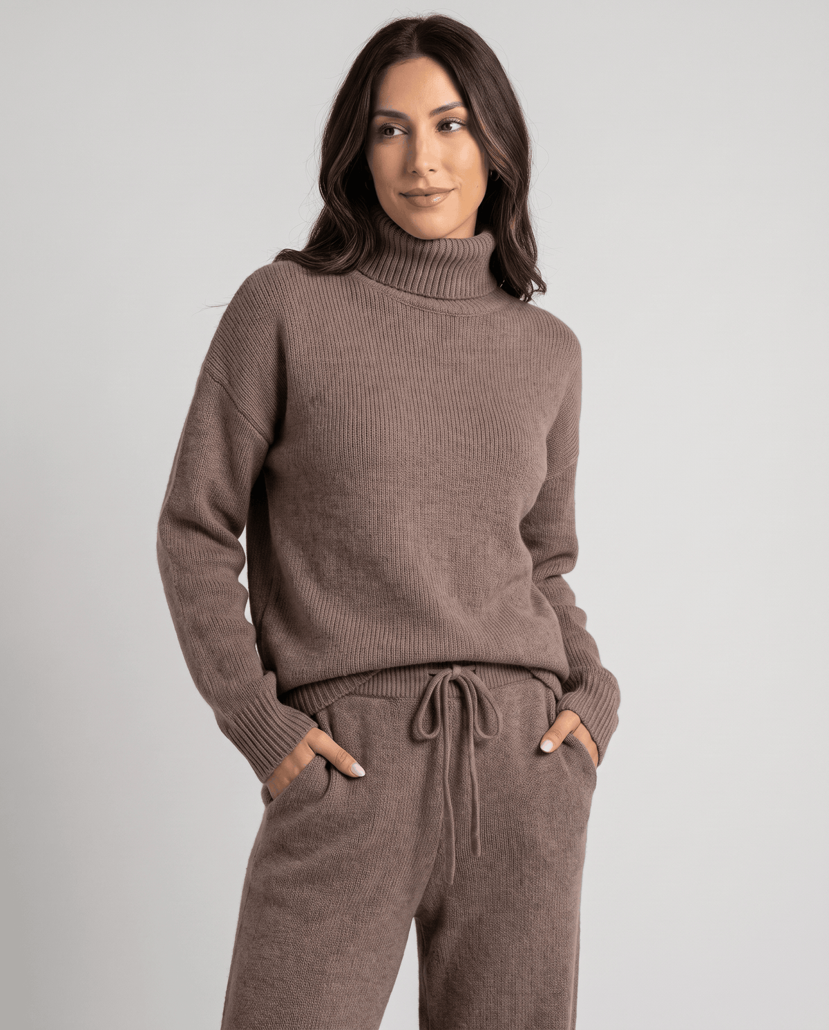 Taupe knit top over drawstring-waist pants with hands resting in the front pockets