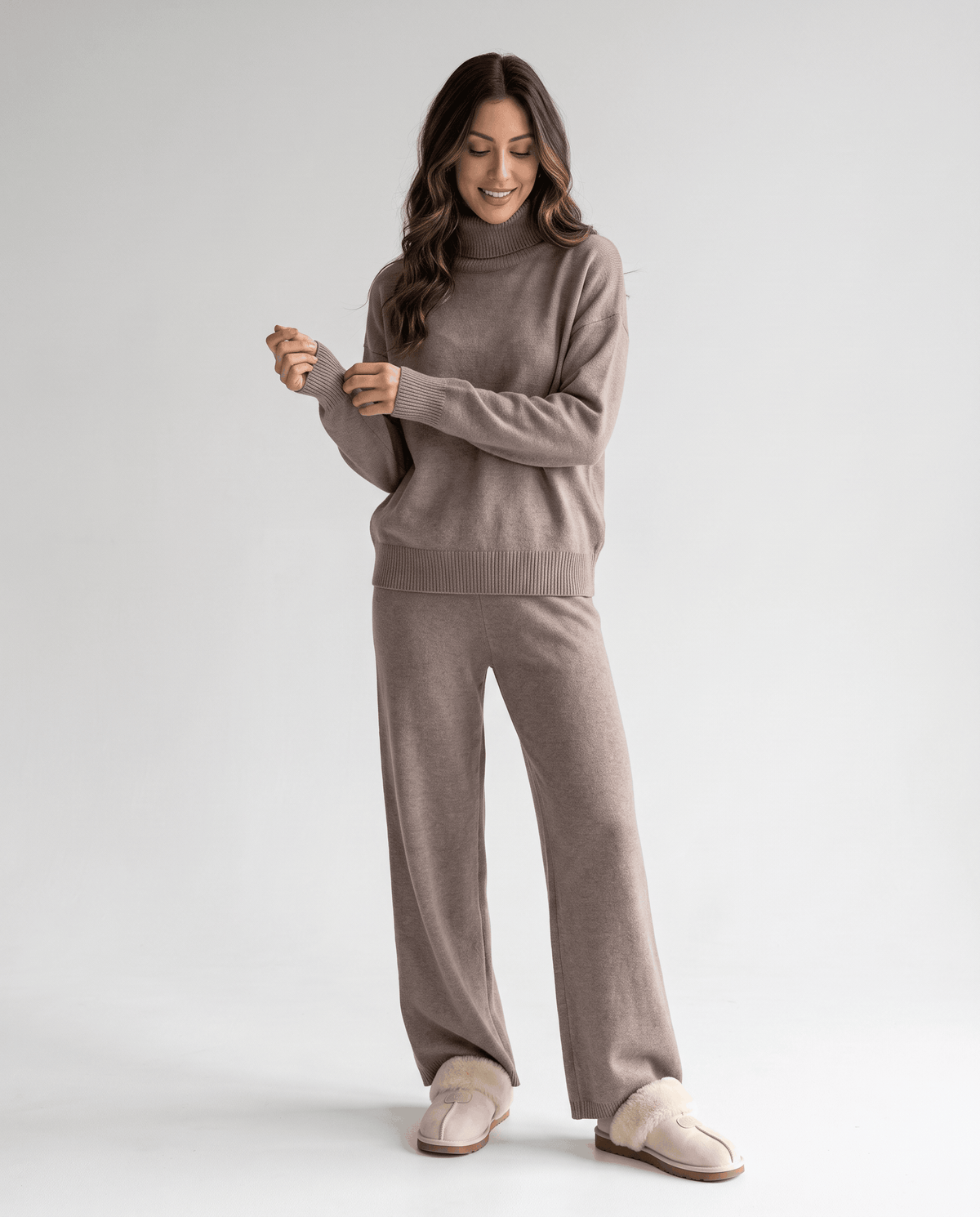 Full-length view of the taupe set with the model adjusting the sleeve cuff