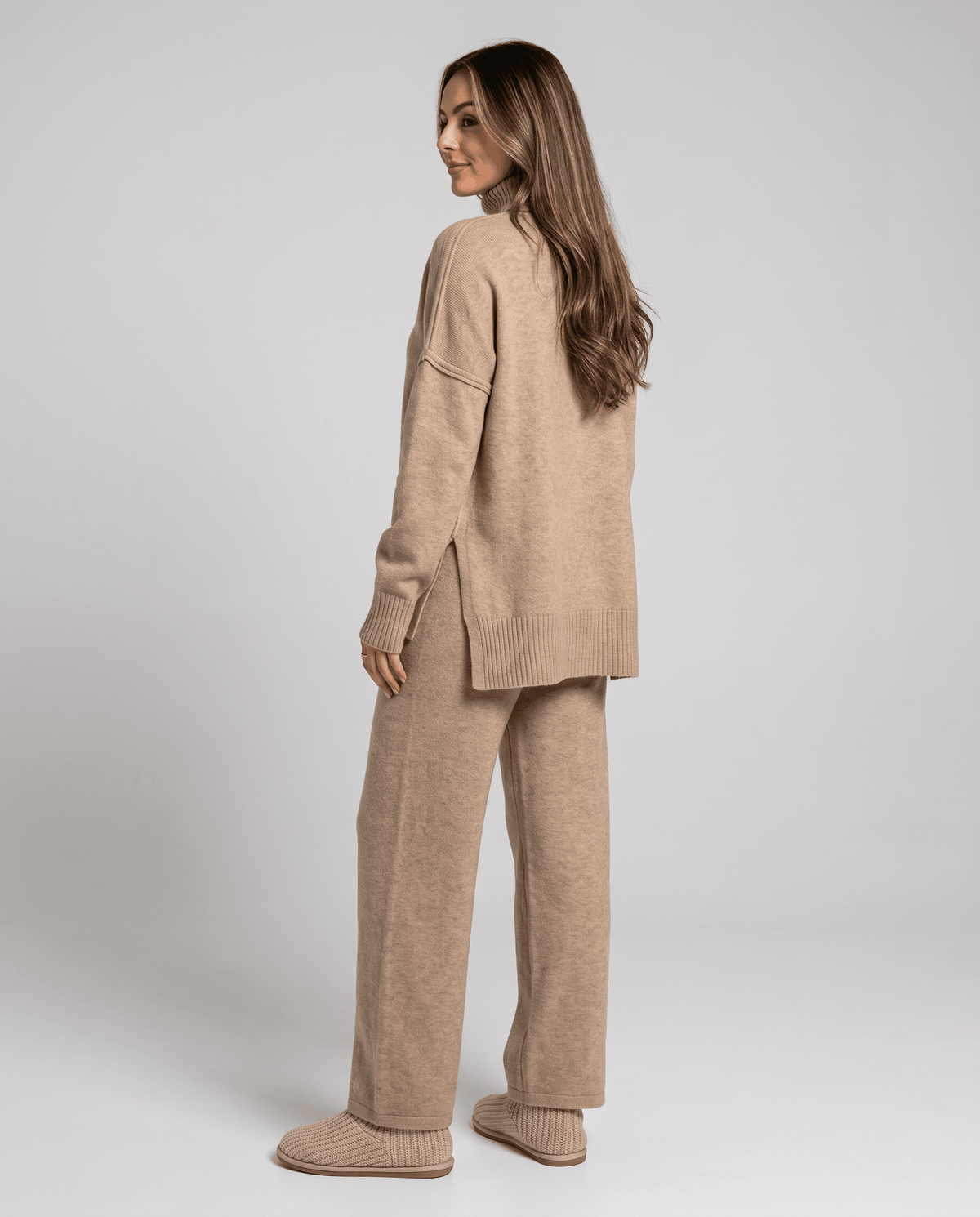 Back view of the beige knit sweater with side slit and wide-leg pants