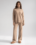 Woman wearing a beige turtleneck loungewear set with oversized sweater and wide-leg pants