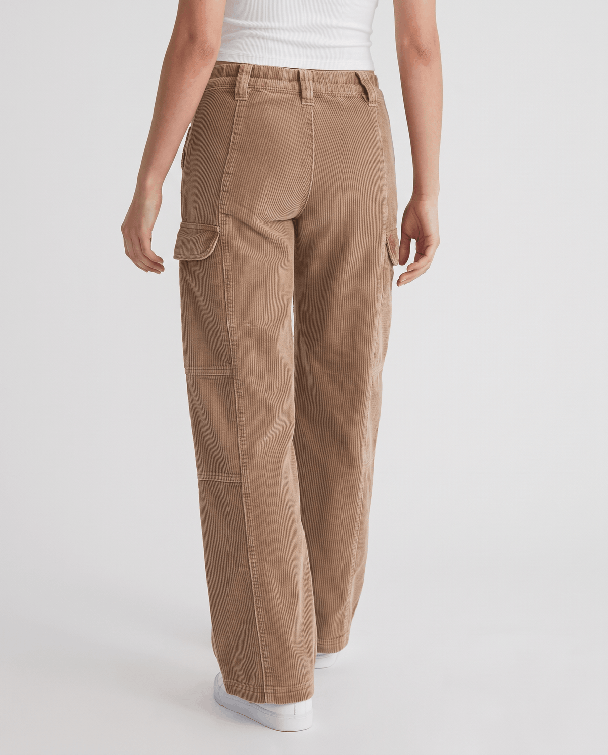 Back view of camel ribbed cargo trousers with thigh flap pockets and white sneakers