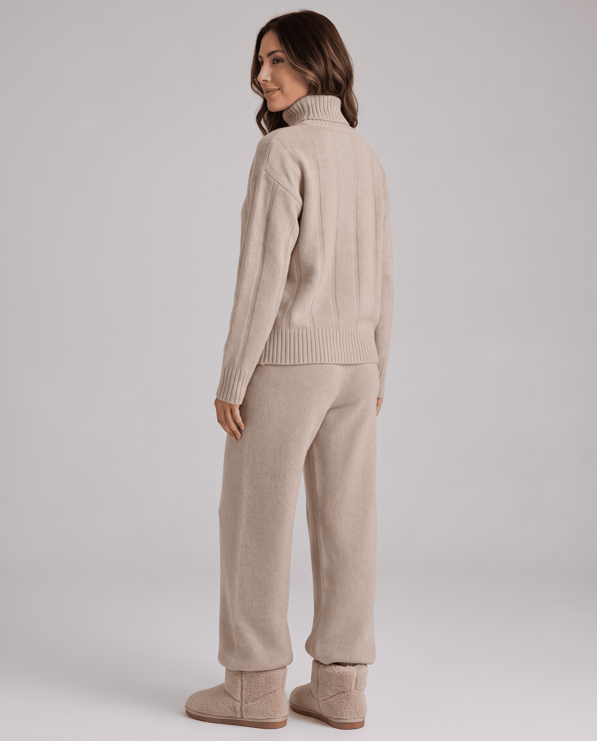 Back view of the beige ribbed top and wide-leg pants with the model looking over her shoulder
