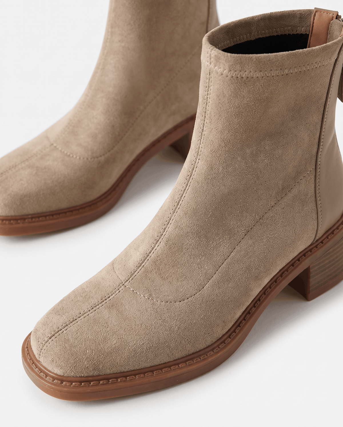 Close-up of the soft suede toe and block heel on a beige ankle boot
