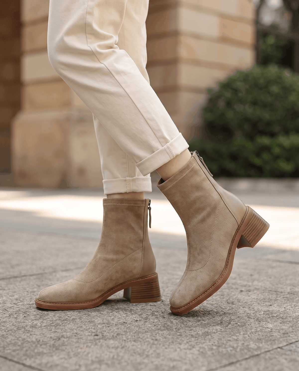Woman walking in beige suede block heel ankle boots with cream trousers