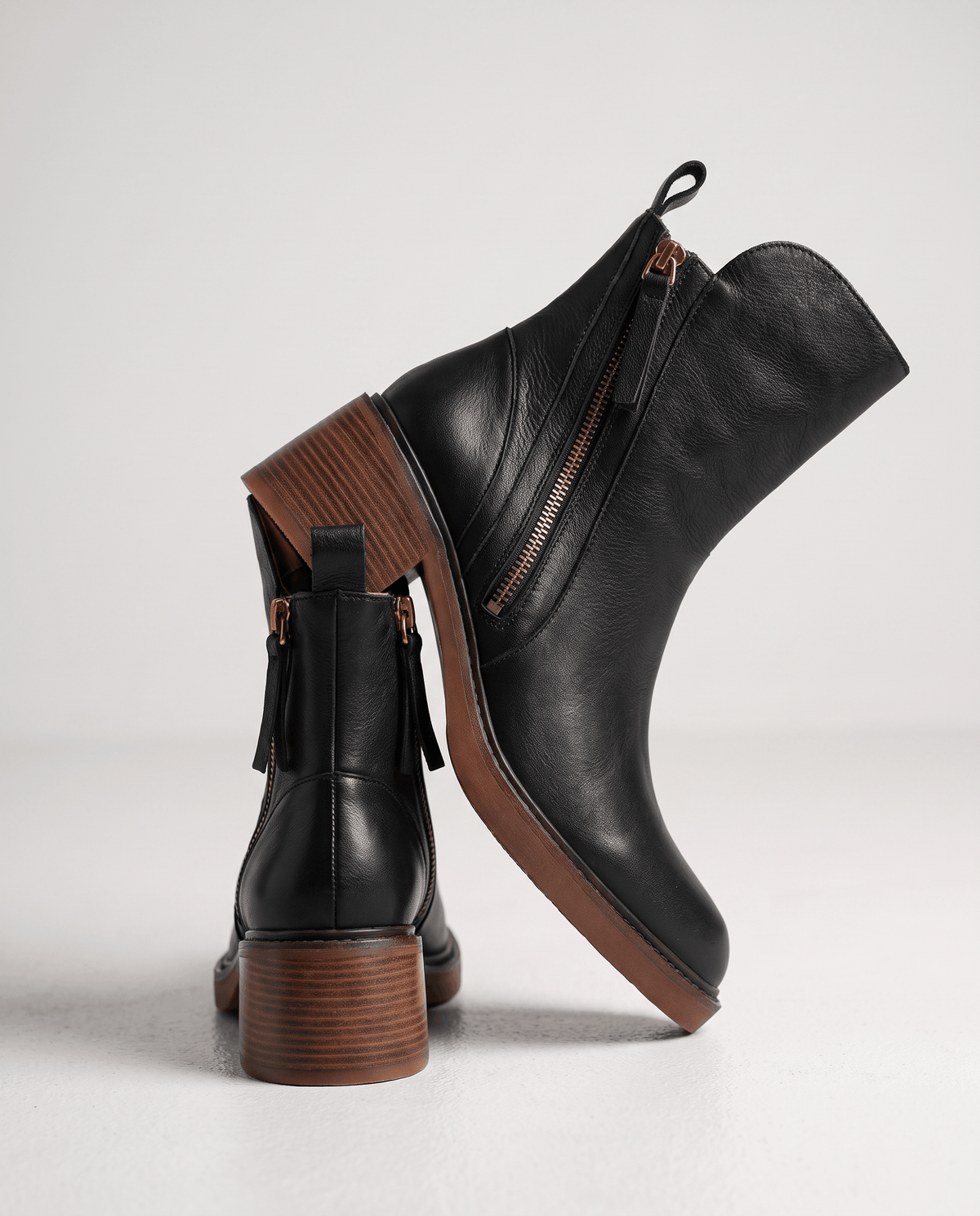 Black block heel ankle boot seen from behind showing the pull tab and stacked heel