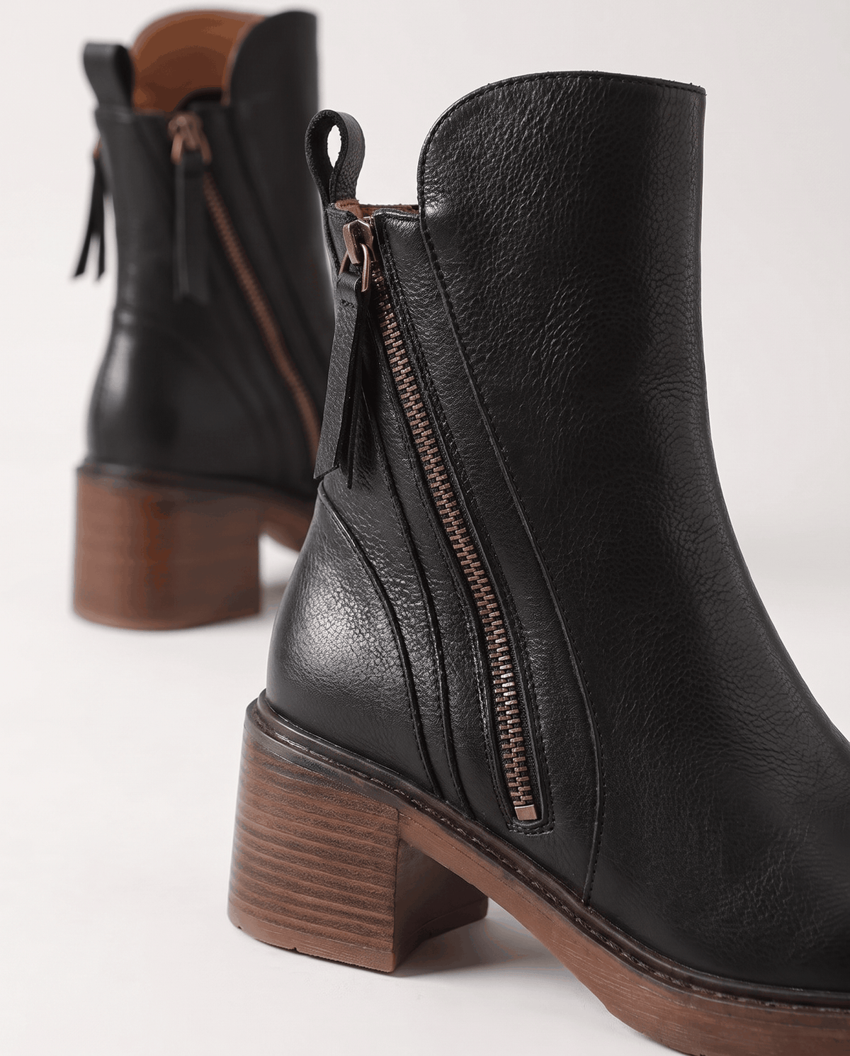 Close-up of the side zip and block heel on a black ankle boot