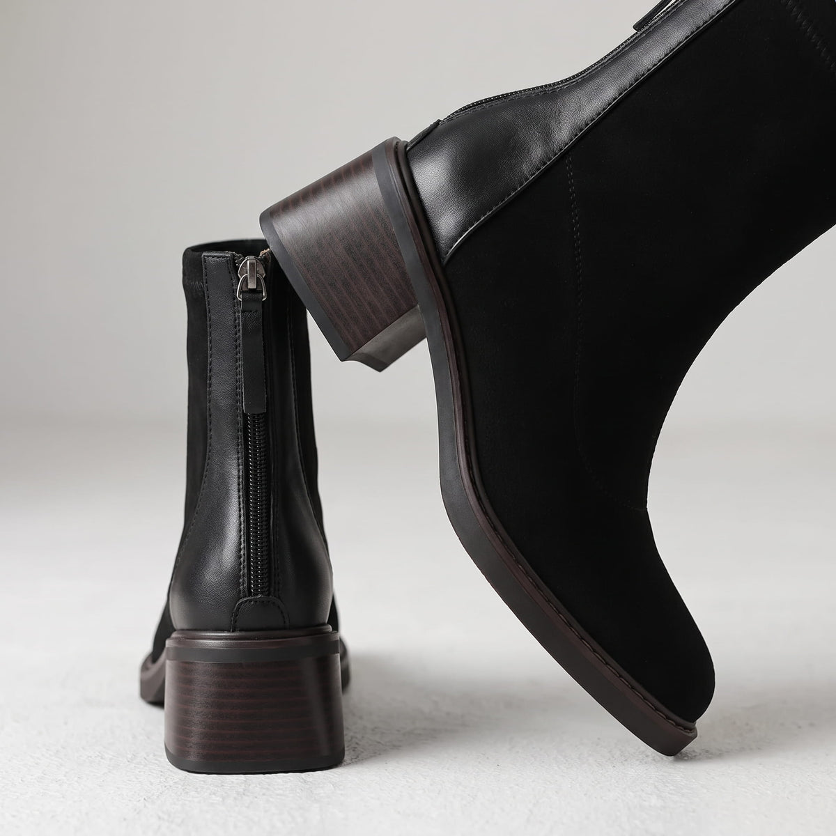 Close-up of the block heel and suede toe on a black ankle boot