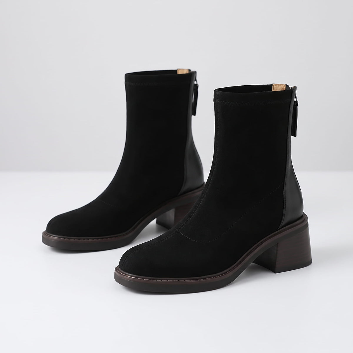 Black suede ankle boots angled to show the block heel and back zip
