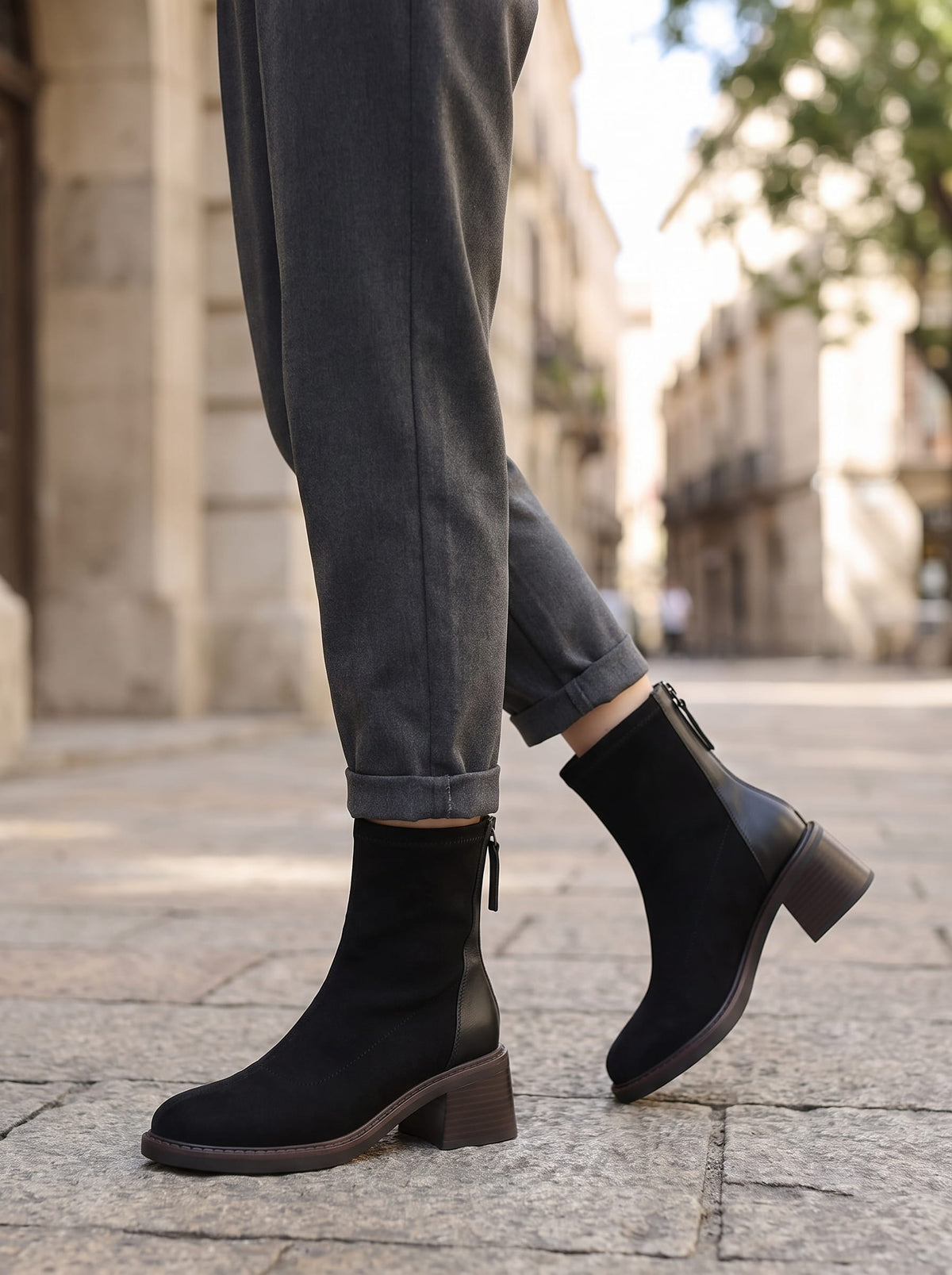 Woman walking in black suede block heel ankle boots with gray jeans outdoors