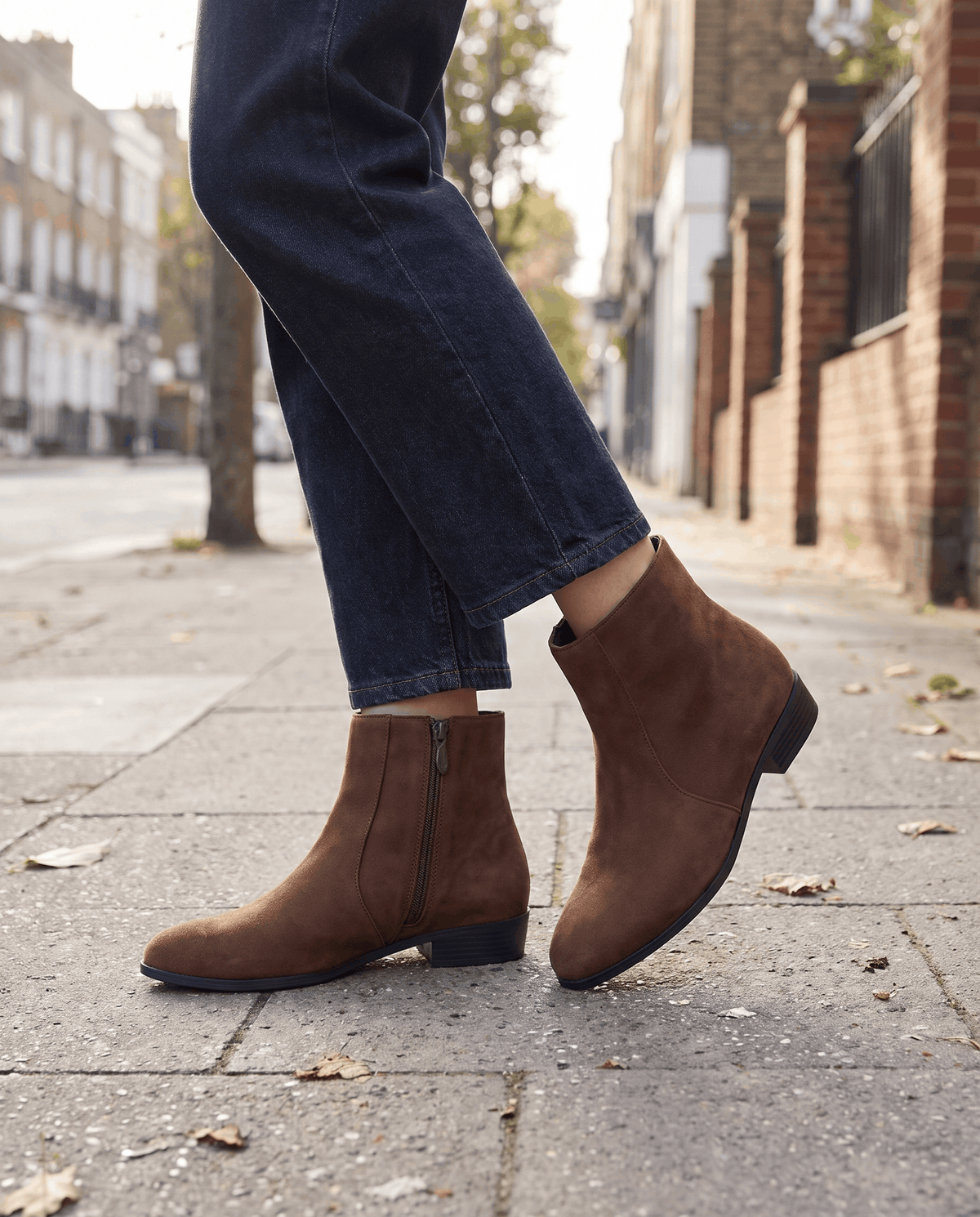 Brown suede-look ankle boots worn with dark jeans on a street