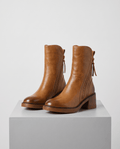 Pair of brown block heel ankle boots with side zip on a gray block