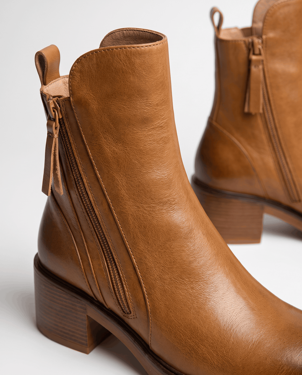 Close-up of the side zip with tassel pull on a brown block heel ankle boot