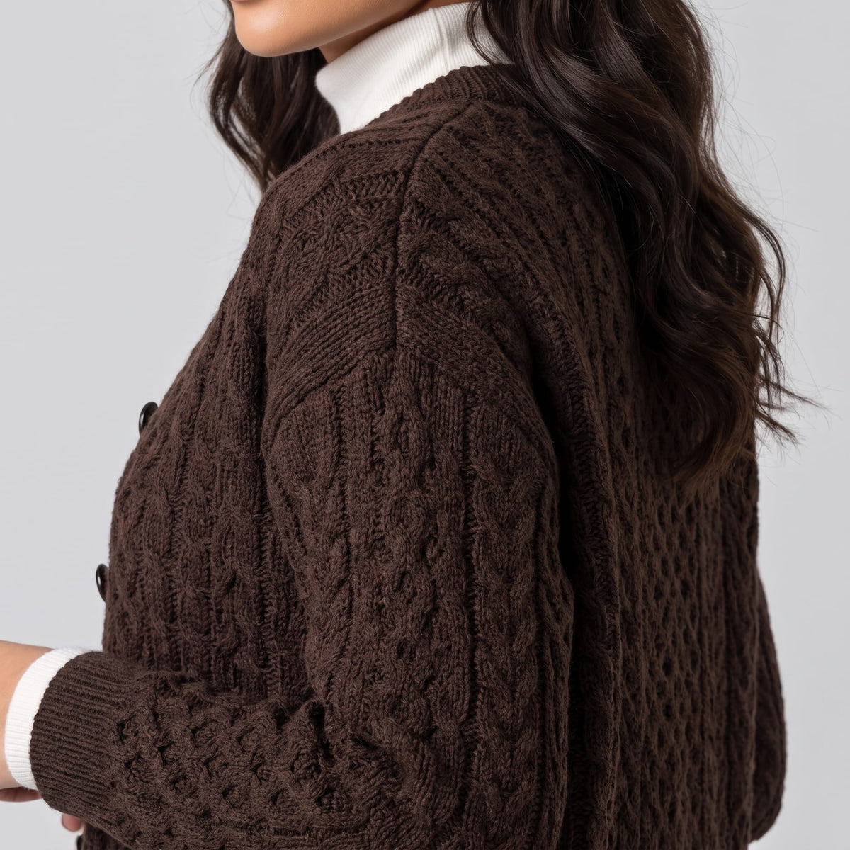 Close side view of dark brown cable-knit cardigan sleeve and shoulder