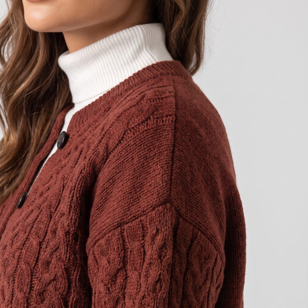 Close side view of maroon cable-knit cardigan sleeve and shoulder