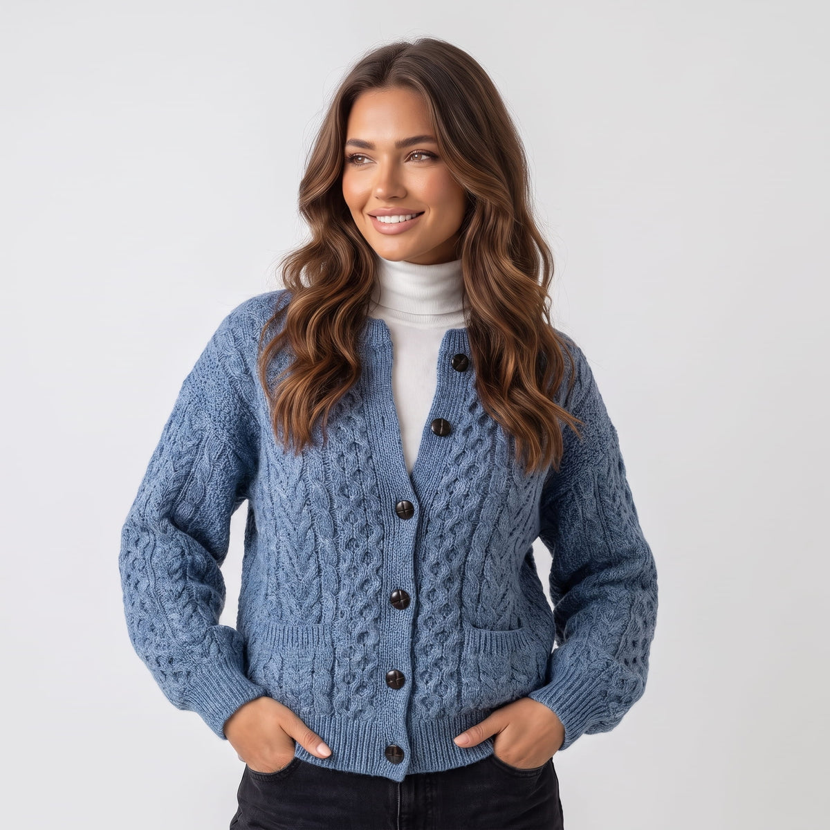 Women's sky blue cable-knit button cardigan worn over a white turtleneck