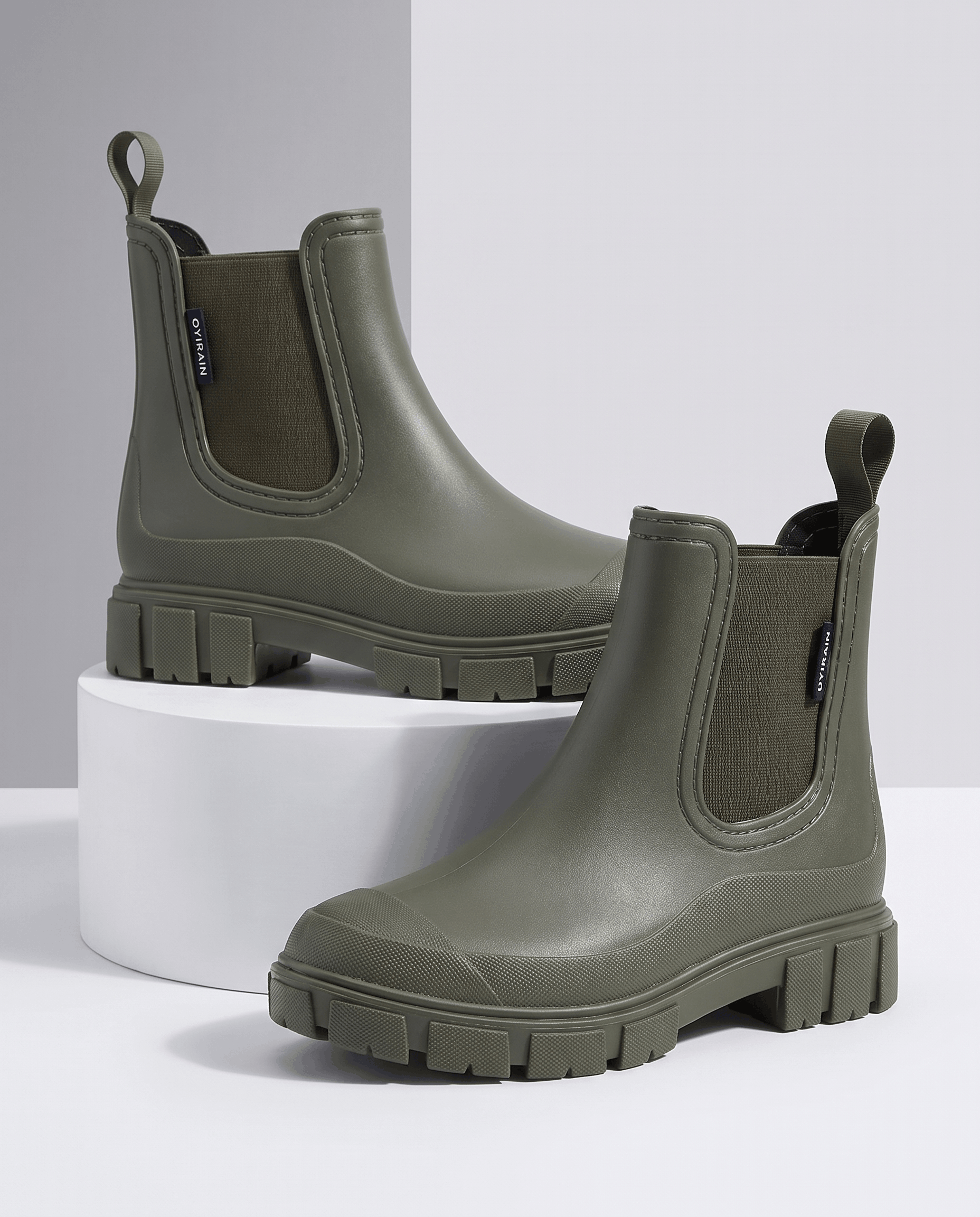 Green Chelsea-style ankle boots with chunky lug soles displayed on white blocks.