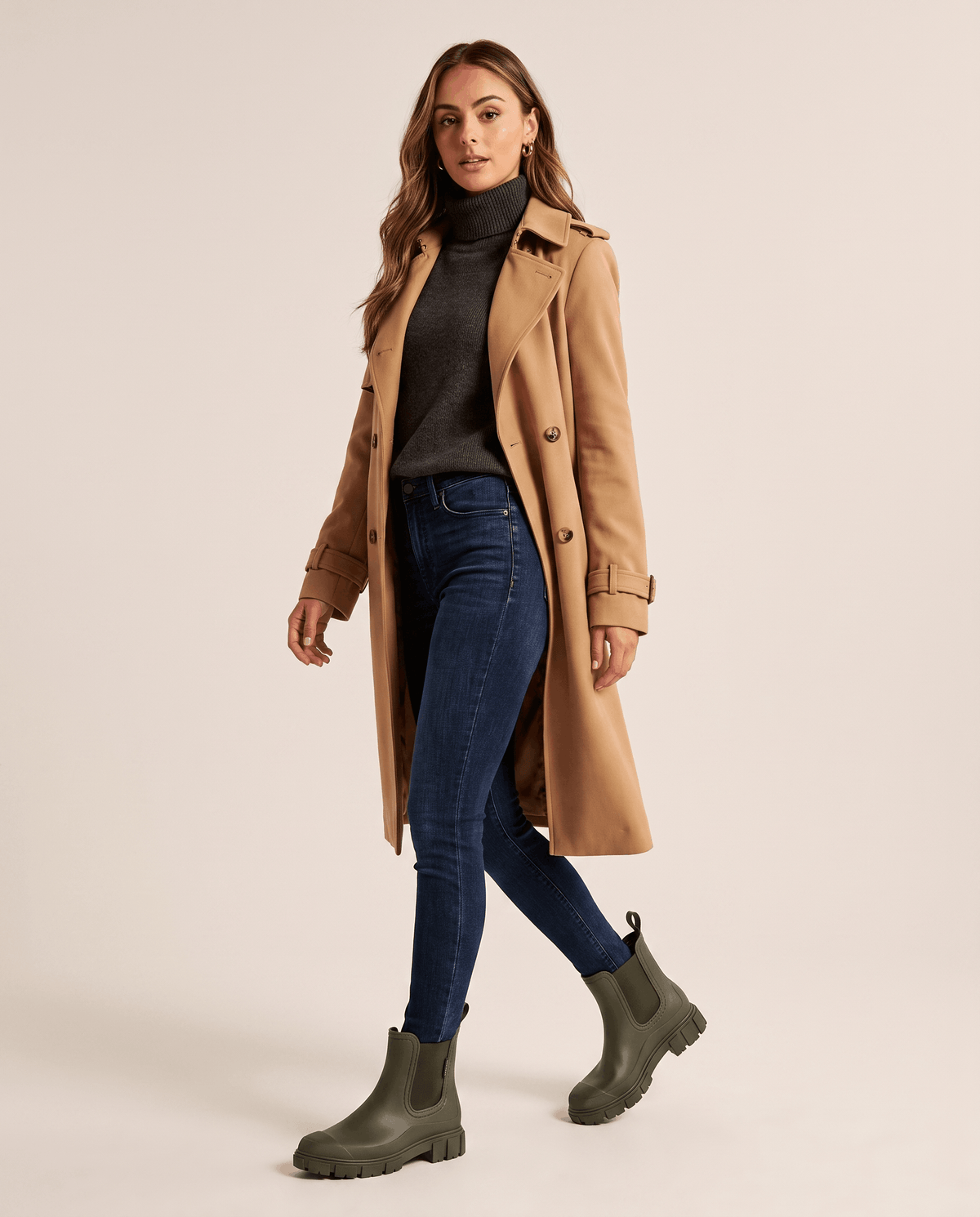 Woman wearing green Chelsea boots with a brown coat and blue jeans.