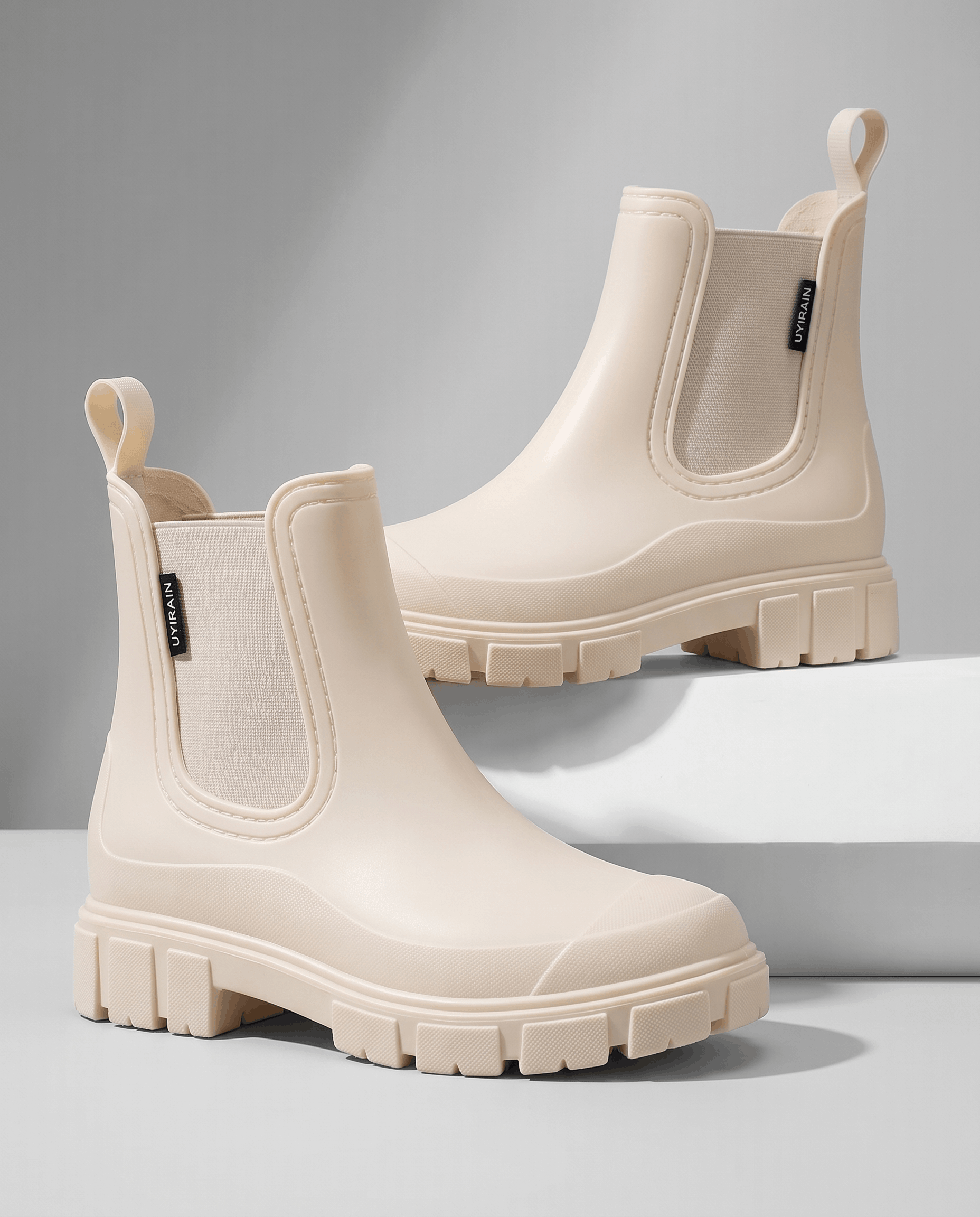 Beige Chelsea boots with chunky lug soles displayed on white blocks.