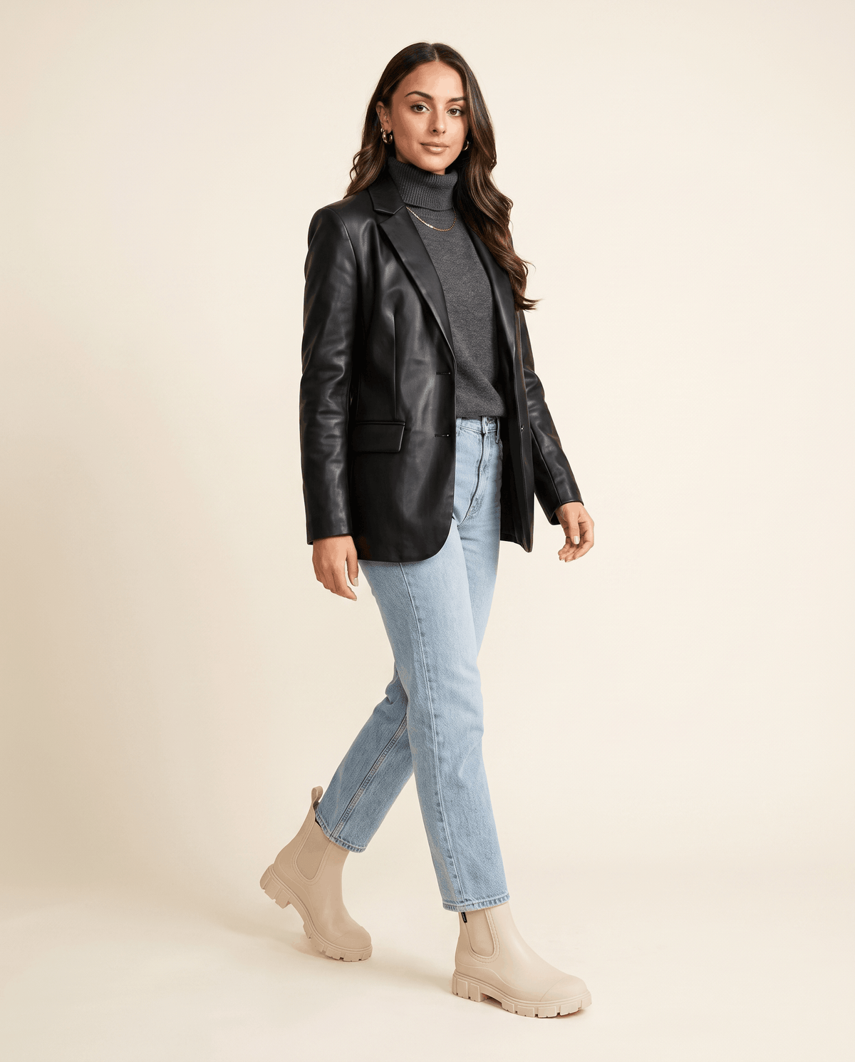 Woman wearing beige Chelsea boots with a black jacket and blue jeans.