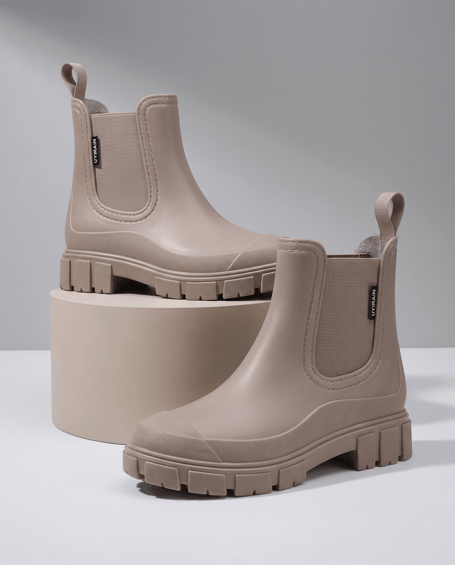Taupe Chelsea boots displayed on white blocks.