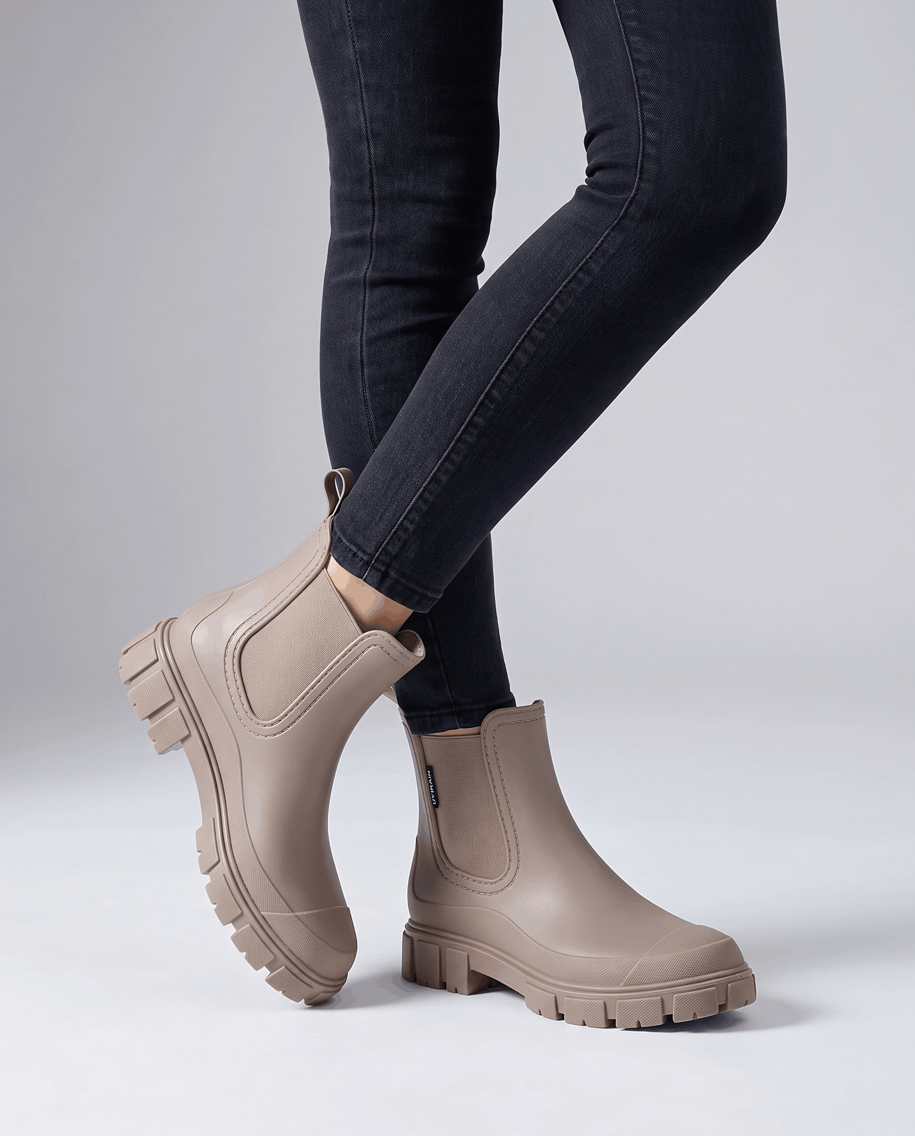 Person wearing white taupe boots with dark jeans in a studio setting.