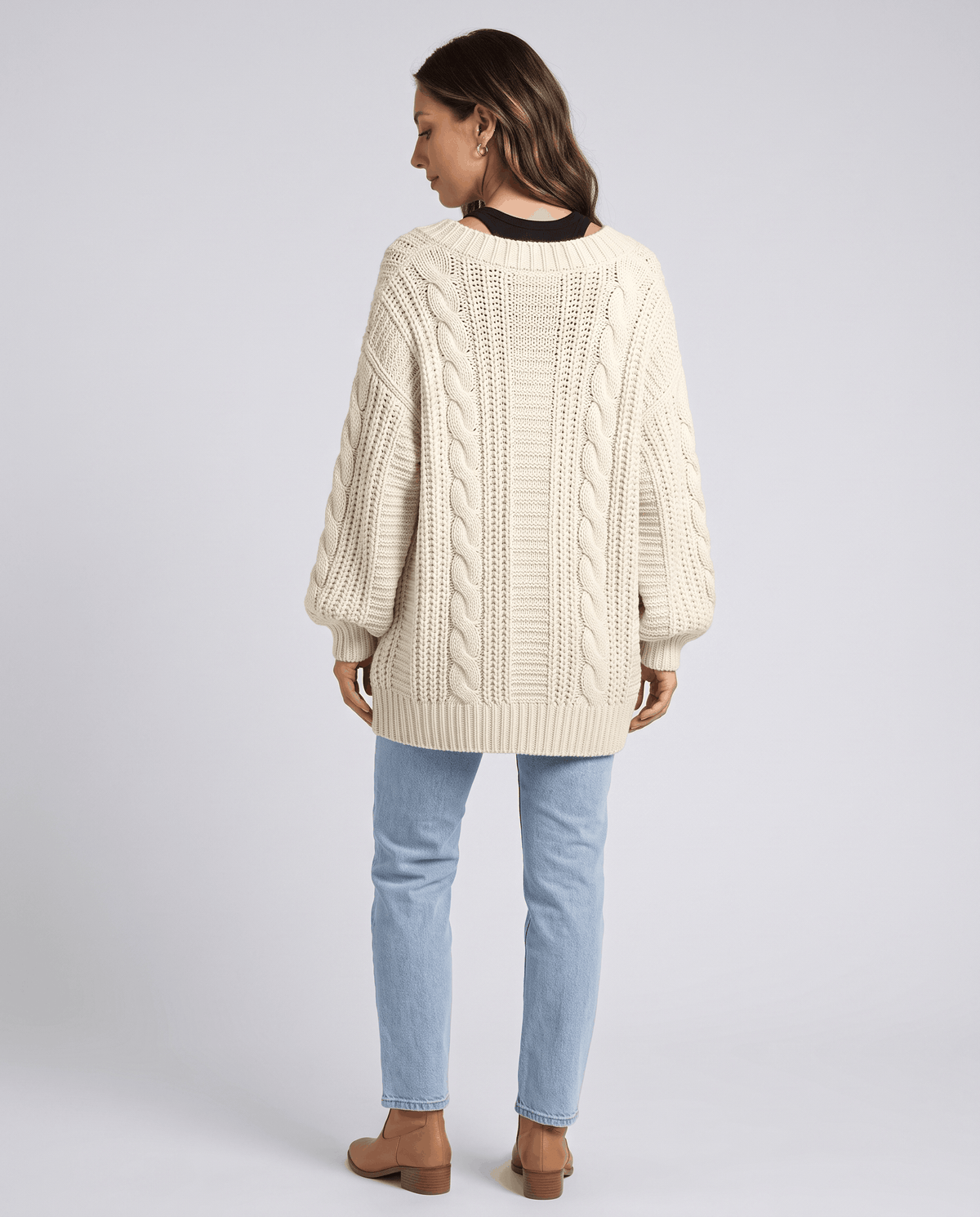 Back view of a cream cardigan showing the cable knit and relaxed shape
