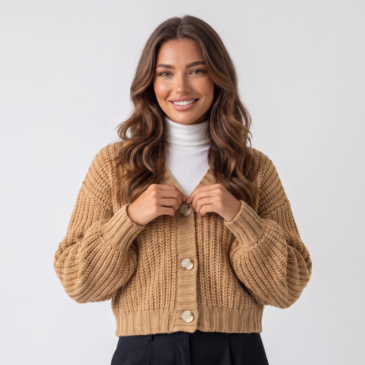 Women's khaki chunky knit button cardigan with balloon sleeves worn over a white turtleneck