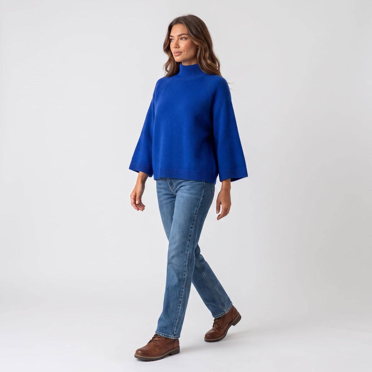 Model walking in the blue boxy sweater with jeans, showing the wide sleeves in motion