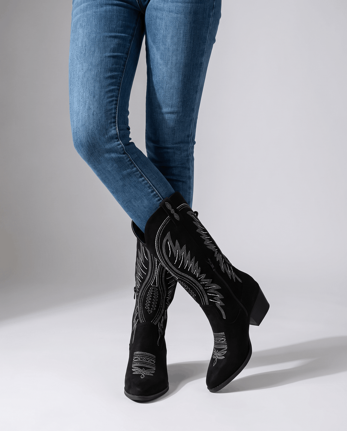Woman in skinny jeans tucked into black boots with white stitching