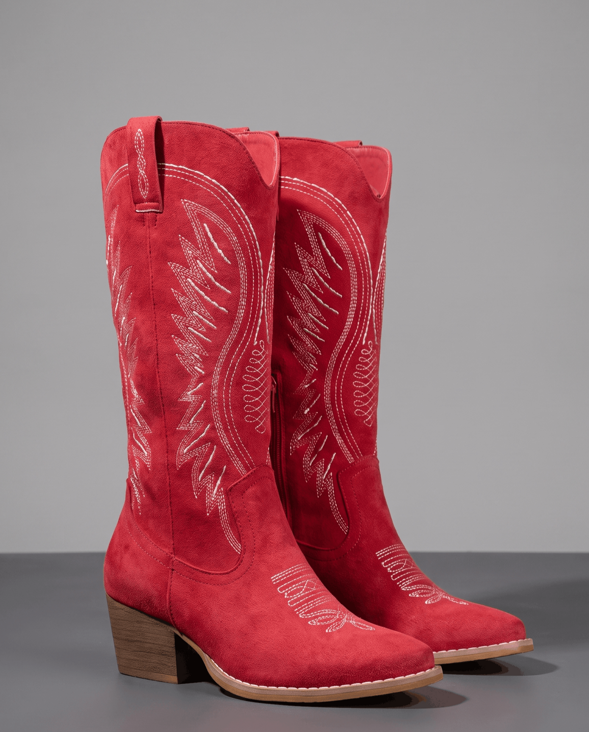 Red pair on a dark floor showing the embroidered shaft and toe cap