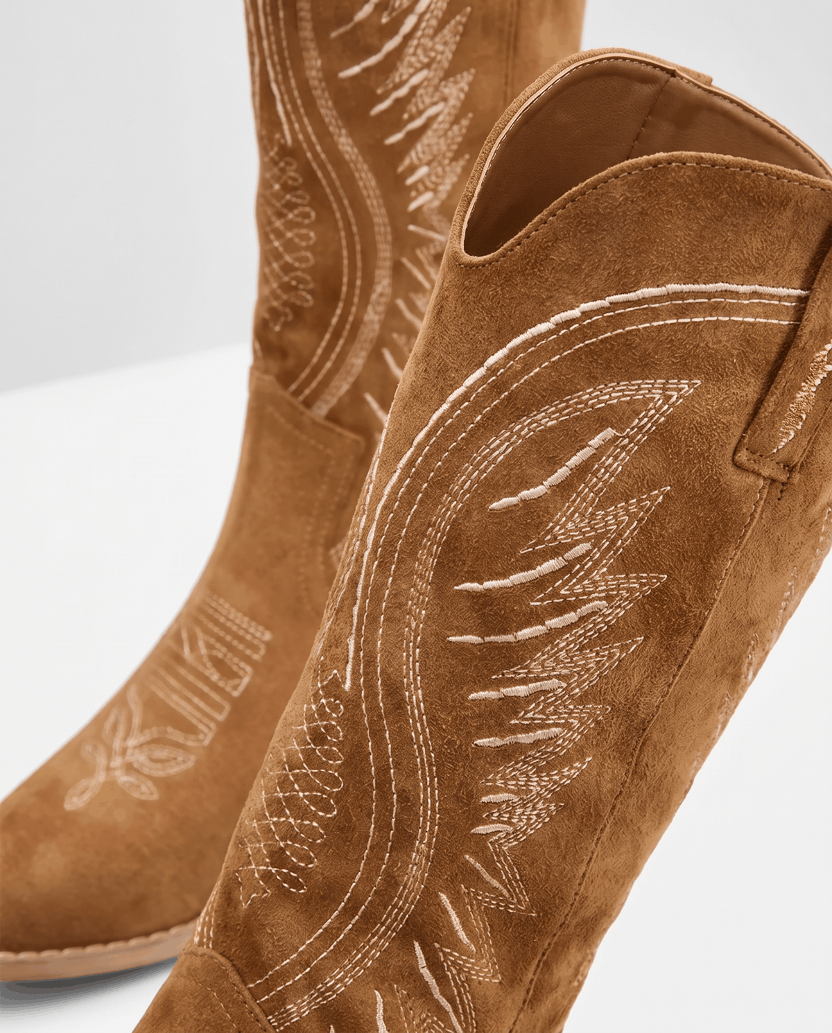 Close view of tonal flame-style embroidery on brown suede-look boot shafts
