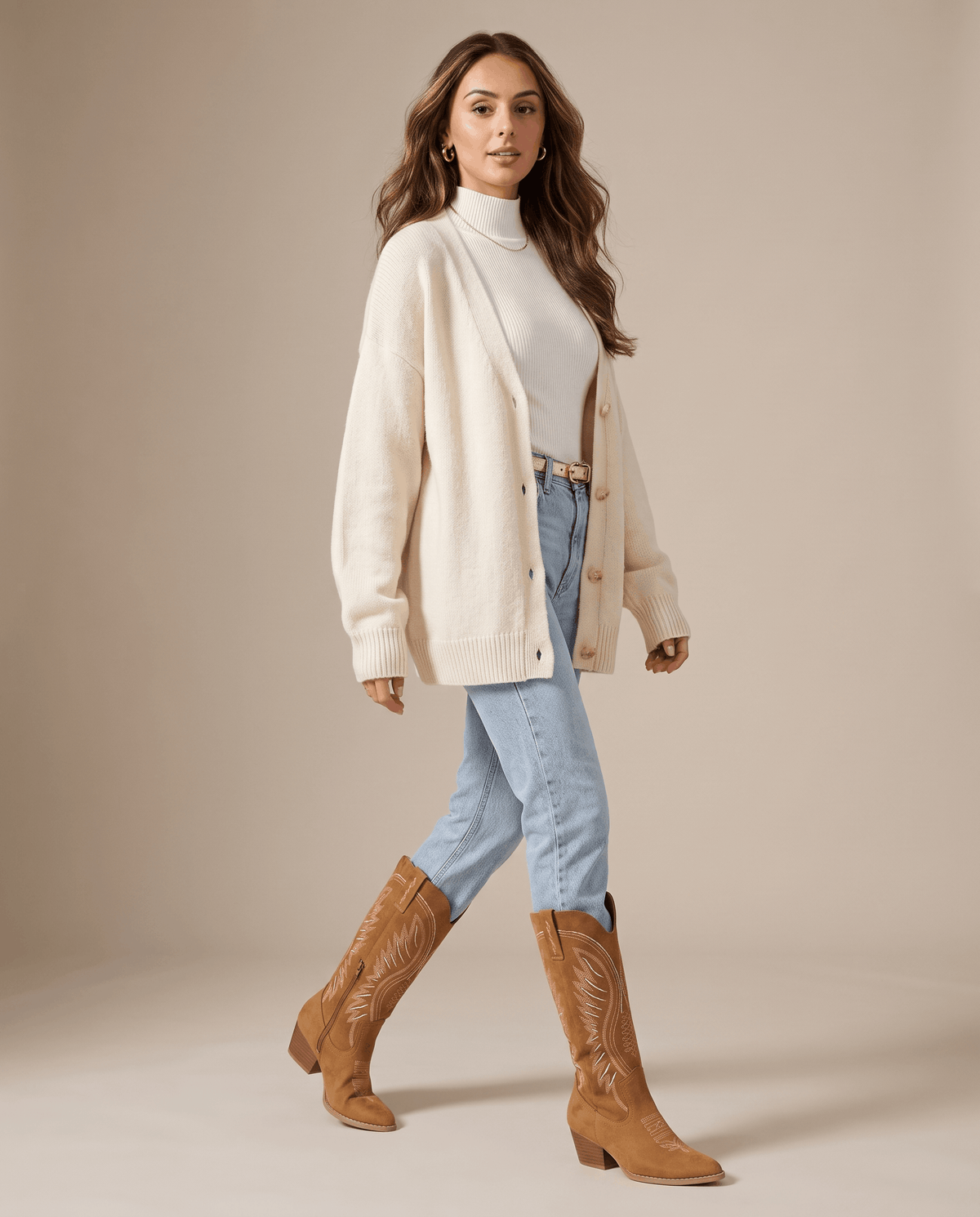 Woman in a cream cardigan and light-wash jeans tucked into brown western boots