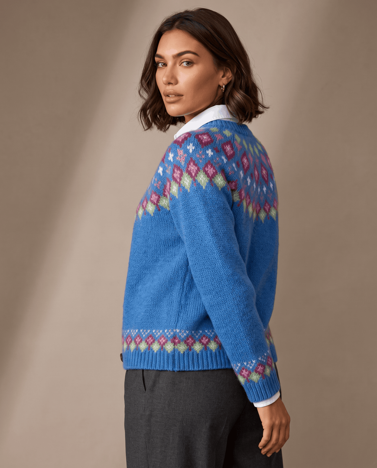 Side view of a blue Fair Isle yoke cardigan worn with dark trousers