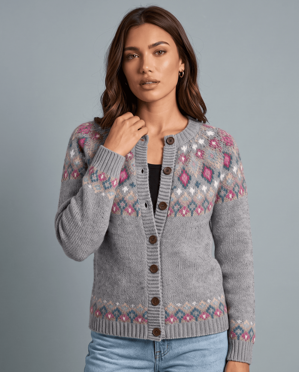 Woman wearing a gray Fair Isle yoke cardigan with one hand at the collar