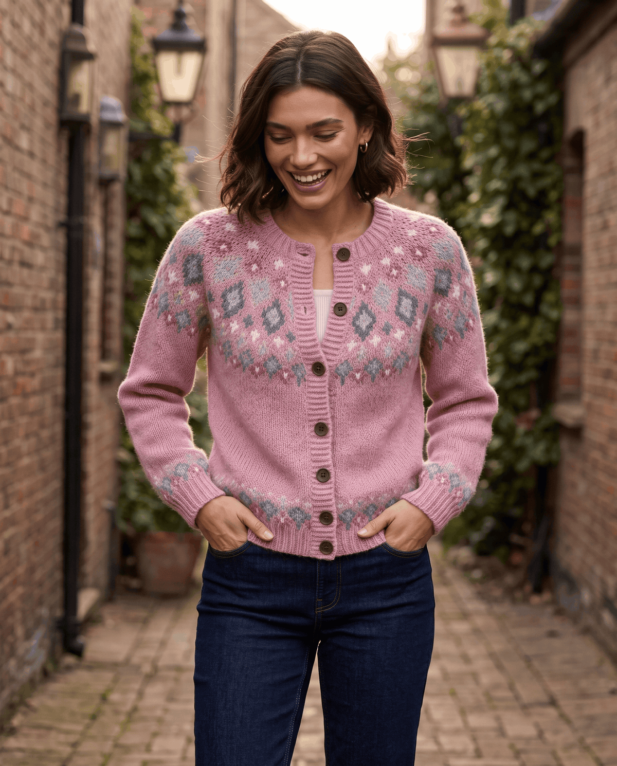 Pink Fair Isle cardigan styled with jeans on a brick-lined city street