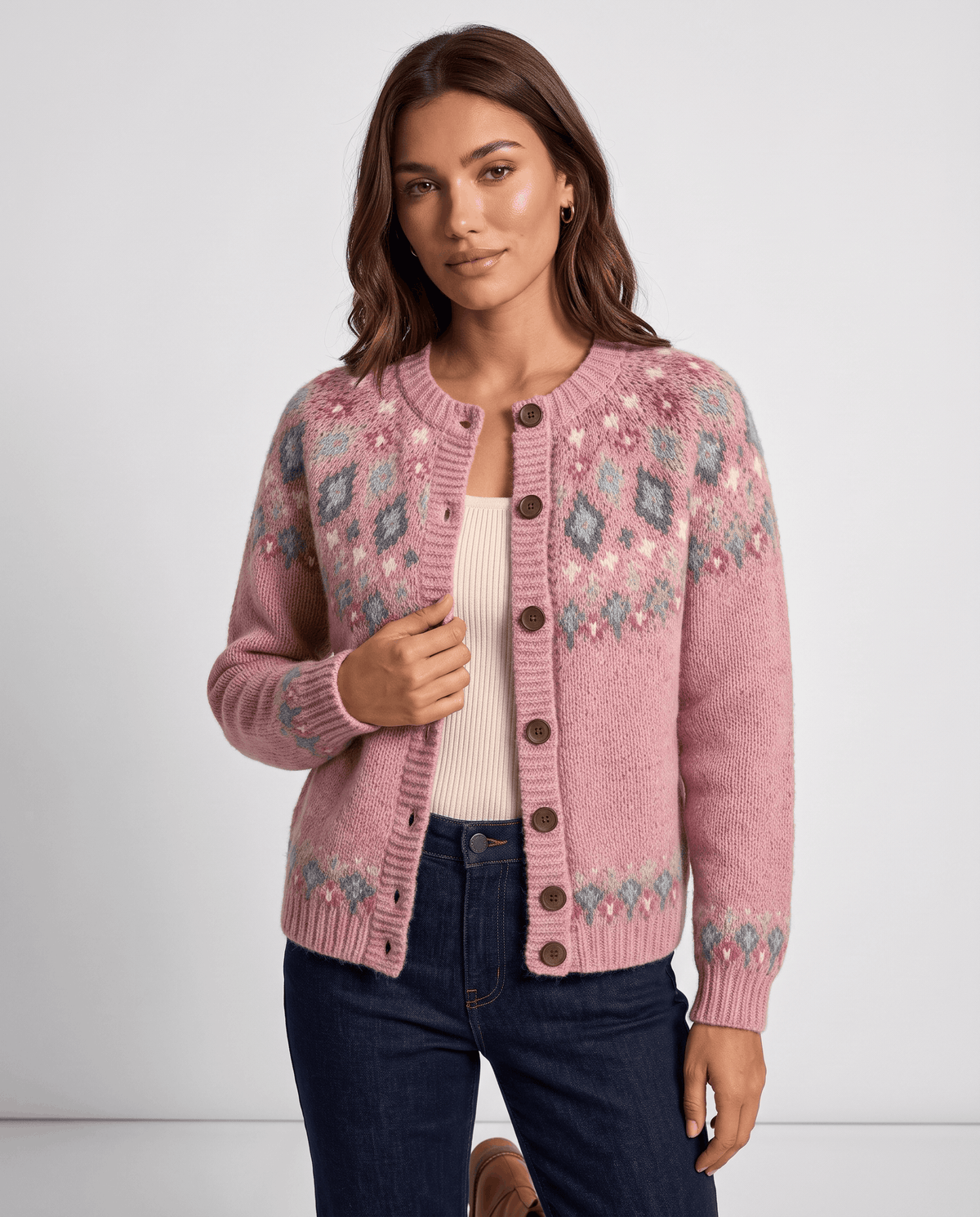 Three-quarter view of a pink Fair Isle cardigan worn with a cream top and dark jeans