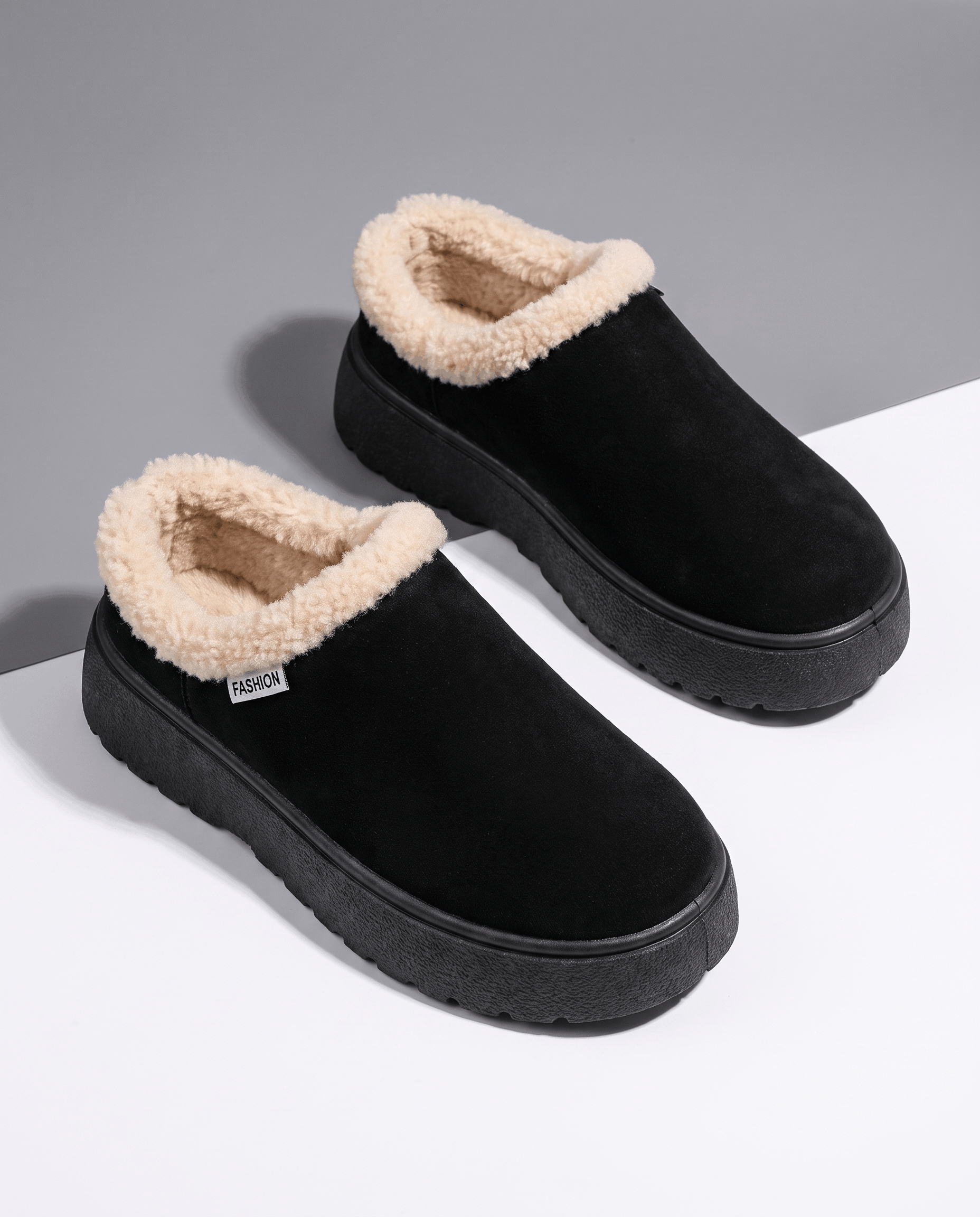 Pair of black fleece-lined slippers with shearling-look cuffs displayed together.