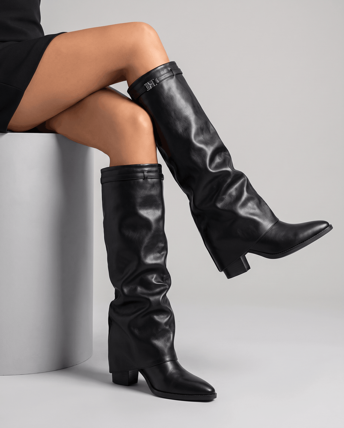 Seated woman with crossed legs showing the black boot's pointed toe and heel