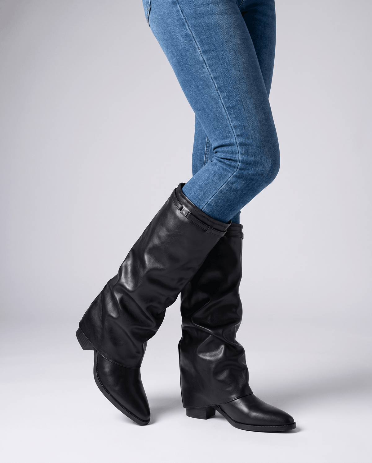 Woman in blue skinny jeans walking in black slouch boots